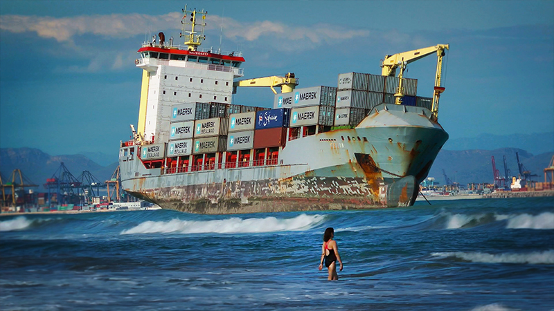 FREIGHTENED Swimmers share the beach with a rusty container ship